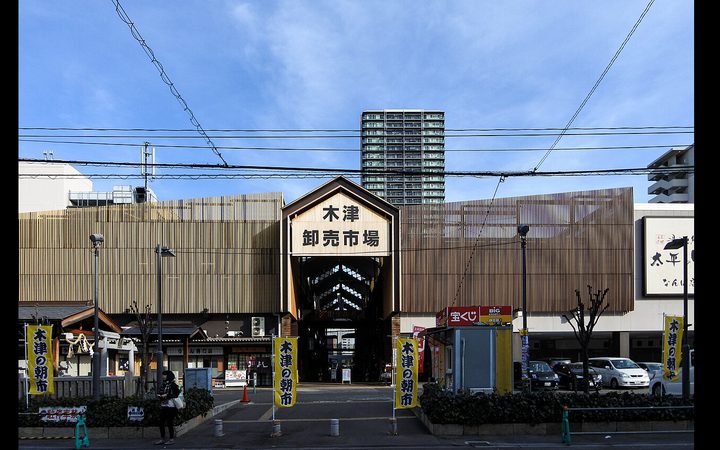 木津卸売市場的木造大門,兩側插著寫「木津の朝市」的黃旗
