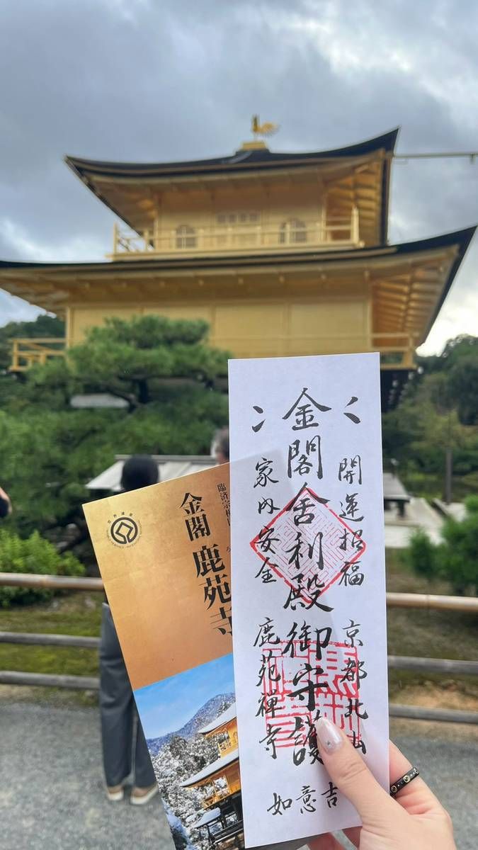 手拿金閣寺的護符門票，後方是金閣