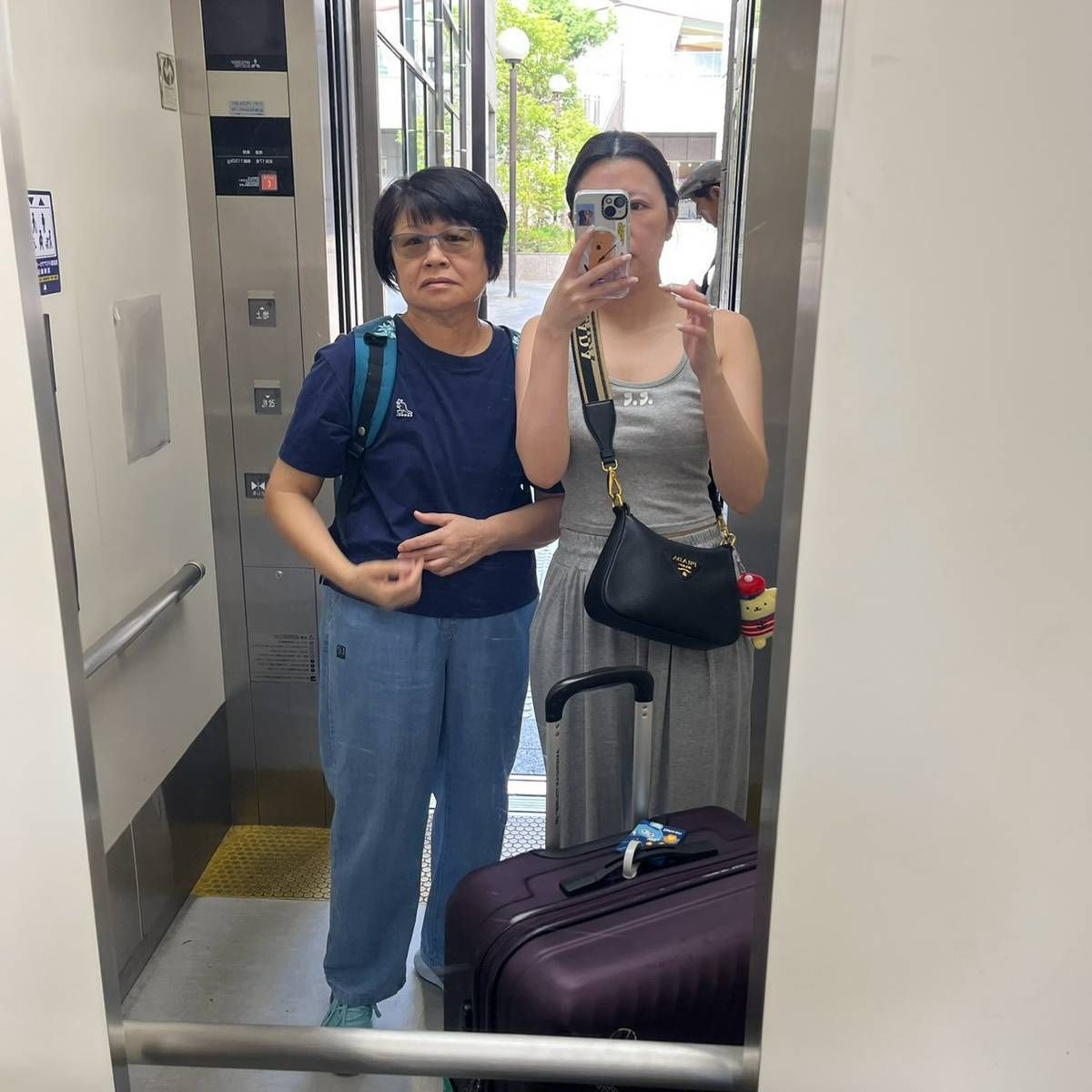 媽媽和小妹帶著行李箱在電梯裡